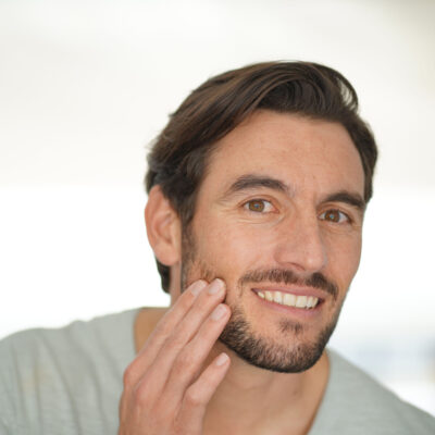 Portrait of attractive man checking wrinkles looking at camera