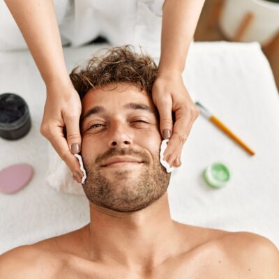 Young hispanic man having facial treatment at beauty center